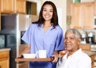 A nurse is holding a tray of coffee and a tray of food in front of an elderly man.