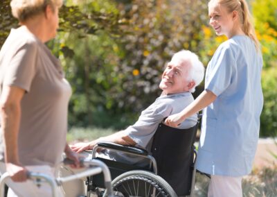 A nurse is helping an elderly man in a wheelchair.