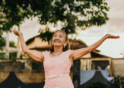 A woman in a pink dress with her arms outstretched.